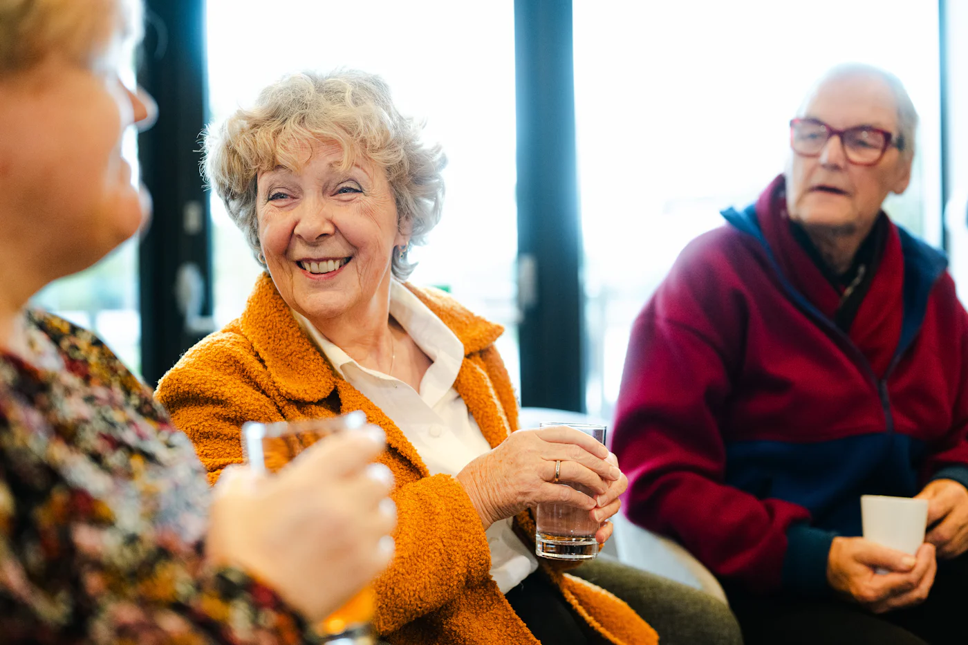 Trois seniors discutent et rient autour d'un café