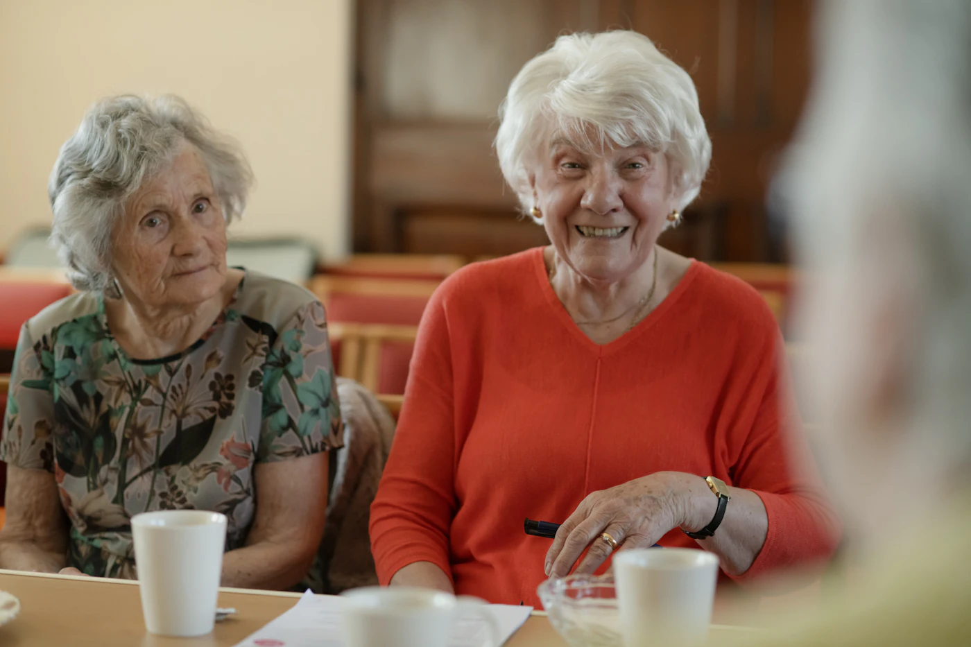 Deux femmes âgées souriantes, attablées ensemble